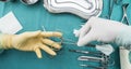Surgeon working in operating room, hands with gloves holding scissors of suture and torundas, conceptual image
