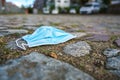Surgical face mask against infection with coronavirus and covid-19 thrown away on a cobblestone square in the city, copy space,