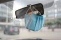 Surgical face mask as protection against covid-19 infection is hanging in a car on the rear view mirror during the coronavirus Royalty Free Stock Photo