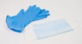 Surgical face mask and blue nitrile gloves on white table. PPE for virus prevention. Royalty Free Stock Photo