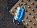 A surgical face mask used for COVID-19 PPE protection, discarded as litter on a pavement / sidewalk Royalty Free Stock Photo