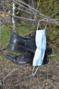 Surgical facemask and a pair of old shues on a tree Royalty Free Stock Photo