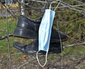 Surgical facemask and a pair of old shues on a tree Royalty Free Stock Photo