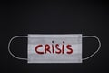 Surgical mask seen from above with word crisis written in red on a black background. Protection against the pandemic