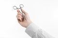 Surgical and Medical theme: doctor's hand in a white lab coat holding a surgical clamp scissors isolated on a white background Royalty Free Stock Photo
