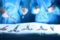 Surgical tools lying on the table while group of surgeons at background operating patient. Steel medical instruments Royalty Free Stock Photo