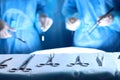 Surgical tools lying on the table while group of surgeons at background operating patient. Steel medical instruments Royalty Free Stock Photo