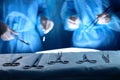 Surgical tools lying on the table while group of surgeons at background operating patient. Steel medical instruments Royalty Free Stock Photo