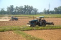 Tractor working ina field opening preparing soil for planting rice.