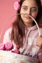 Surprided brunette girl in pink hoodie holding basket of spring flowers, female with flower in her hair Royalty Free Stock Photo