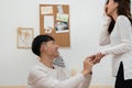 A surprise Asian couple proposes to marry. Young man kneeling and wearing a ring on his girlfriend finger