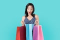 Surprise asian woman for gifts in the shopping bags on light blue background.