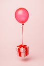 Surprise composition with color balloon and beautiful gift box with bow flying on pastel pink background. Creative birthday or Chr Royalty Free Stock Photo