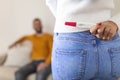 Surprise darling! Woman is hiding pregnancy test behind her back. Woman hiding positive pregnancy test from her spouse for a Royalty Free Stock Photo