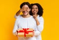 Surprise. Black girlfriend covering her boyfriend`s eyes while giving present Royalty Free Stock Photo