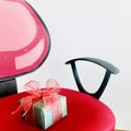 A surprise green gift box on red chair over white background. Royalty Free Stock Photo