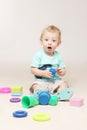 Surprised adorable baby boy sitting on the floor and playing with his toys. Royalty Free Stock Photo