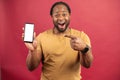 African-American guy points at empty phone screen isolated on red