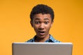 Surprised Afro American teen looks at laptop