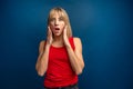 Surprised amazed beautiful blonde woman with wide open mouth looking at camera, smiling. Girl posing on blue background Royalty Free Stock Photo