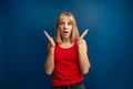 Surprised amazed beautiful blonde woman with wide open mouth looking at camera, smiling. Girl posing on blue background Royalty Free Stock Photo