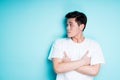 Surprised asian guy standing on a blue background with his arms crossed over his chest and looking to the side Royalty Free Stock Photo