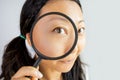 Surprised asian woman looking at camera through magnifying glass, isolated on white background Royalty Free Stock Photo