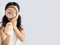 Surprised asian woman looking at camera through magnifying glass, isolated on white background Royalty Free Stock Photo