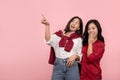 Surprised Asian woman wearing a red shirt and jeans covers her mouth with her hand. Young woman with short brown hair is excited