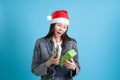 surprised Asian young woman in Santa Claus hat opens new year gift box, on blue background Royalty Free Stock Photo