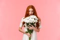 Surprised attractive redhead girl receive romantic valentines day gift, looking at beautiful bouquet of flowers amazed Royalty Free Stock Photo