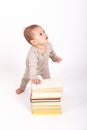 Surprised baby boy in cream clothes playing with books Royalty Free Stock Photo