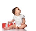 Surprised baby in jumpsuit sitting with gift box looking aside Royalty Free Stock Photo