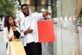 Surprised black couple with shopping bags pointing at window Royalty Free Stock Photo