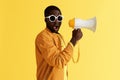 Surprised black man with megaphone on yellow background