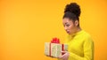 Surprised black woman holding birthday gift box, unexpected present, background