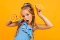 Surprised blond attractive girl with oranges on a yellow background