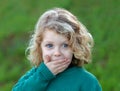 Surprised blond child covering his mouth Royalty Free Stock Photo