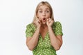 Surprised blond girl pucker lips, say wow and looking amazed, hear shocking announcement, standing in green dress over