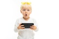 Surprised blond kid with a phone in a horizontal position in his hands on a white background