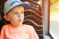 Surprised boy looking out window of bus. Cute little boy in cap sitting in bus. Travel, lifestyle and people concept. Summer holod Royalty Free Stock Photo