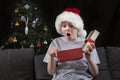 Surprised boy in Santa hat with an open gift box in his hands. Gifts for New Year and Christmas Royalty Free Stock Photo