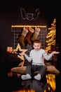 Surprised boy is waiting for a Christmas present at his house near Christmas tree and fireplace Royalty Free Stock Photo