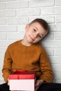 Surprised boy in a yellow sweater holds a green round gift with a red ribbon Royalty Free Stock Photo