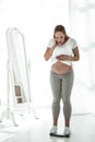 Surprised brown-haired pregnant woman checking her weight Royalty Free Stock Photo