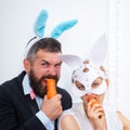 Surprised bunny couple wearing bunny ears and eat carrot. easter.