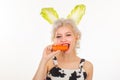 Surprised bunny woman eat carrot. Happy easter and funny easter day. Young woman wearing bunny ears on Easter day.