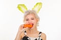 Surprised bunny woman eat carrot. Happy easter and funny easter day. Young woman wearing bunny ears on Easter day.