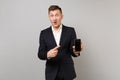 Surprised business man keeping mouth open, pointing index finger on mobile phone with blank empty screen isolated on Royalty Free Stock Photo