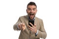 Surprised businessman with beard holding phone and pointing finger Royalty Free Stock Photo